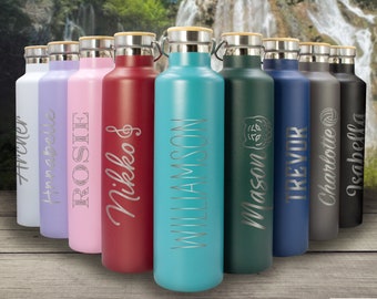 Op de afbeelding: Tien gepersonaliseerde waterflessen van roestvrij staal met bamboe deksels. De flessen zijn in verschillende kleuren verkrijgbaar, waaronder turquoise, groen, blauw, grijs en roze. Elke fles heeft een gegraveerde naam.