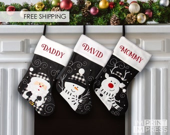 May include: Three black and white Christmas stockings with personalized names "Daddy", "David", and "Mommy". Each stocking features a different festive design: Santa Claus, a snowman, and a reindeer.