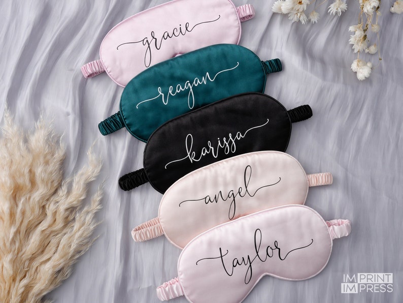 May include: Five personalized sleep masks in pink, green, and black with names embroidered in white. The names are "gracie", "reagan", "karissa", "angel", and "taylor".