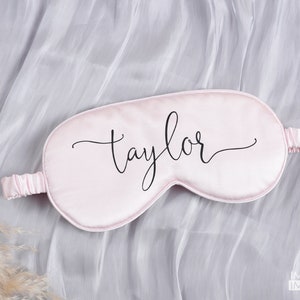 May include: A pink satin sleep mask with the name "Taylor" written in black cursive script.