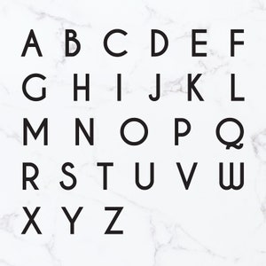Op de afbeelding: Zwart-witte alfabetletters in een moderne lettertype stijl. De letters zijn gerangschikt in rijen op een witte marmeren achtergrond.