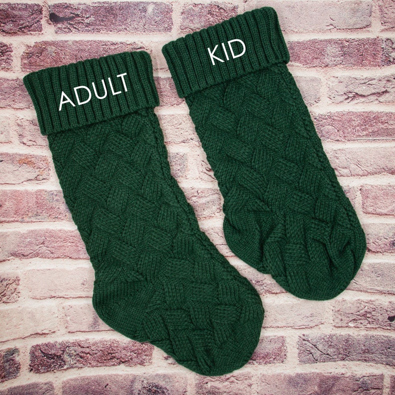 May include: Two green knitted Christmas stockings with white embroidered text. The larger stocking says "Adult" and the smaller stocking says "Kid".