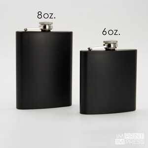Puede incluir: Dos matraces de metal negro con tapas y bisagras plateadas. El matraz de la izquierda est&aacute; etiquetado como "8 oz." y el matraz de la derecha est&aacute; etiquetado como "6 oz."