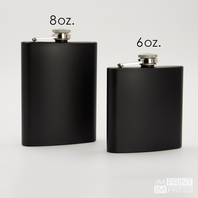Puede incluir: Dos matraces de metal negro con tapas y bisagras plateadas. El matraz de la izquierda est&aacute; etiquetado como "8 oz." y el matraz de la derecha est&aacute; etiquetado como "6 oz."