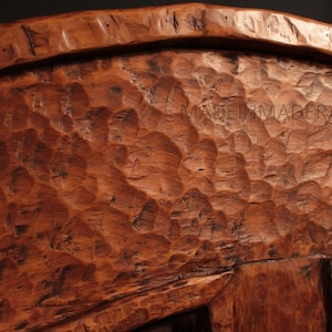 Puede incluir: Primer plano de un cuenco de madera con una superficie rugosa y texturizada. El cuenco est&aacute; hecho de madera marr&oacute;n oscura y tiene una forma redondeada.