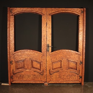 Puede incluir: Un par de puertas dobles de madera con paneles de vidrio arqueados y tallas intrincadas. Las puertas est&aacute;n te&ntilde;idas de un rico color marr&oacute;n y cuentan con una manija y bisagras de metal. Las puertas est&aacute;n etiquetadas con "MADE IN MADERA.COM".