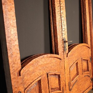 Puede incluir: Un par de puertas dobles de madera con intrincados tallados y paneles de vidrio arqueados. Las puertas est&aacute;n hechas de una madera rica y oscura y tienen un aspecto r&uacute;stico y antiguo.