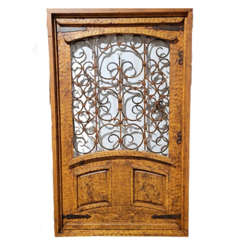 May include: A wooden door with a wrought iron decorative insert. The door is a medium brown colour and has a distressed finish. The door has two panels at the bottom.
