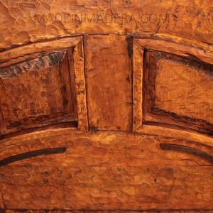 Puede incluir: Primer plano de una puerta de armario de madera con dos paneles y bisagras de hierro decorativas. La madera es de un color marr&oacute;n intenso y tiene una superficie rugosa y texturizada.