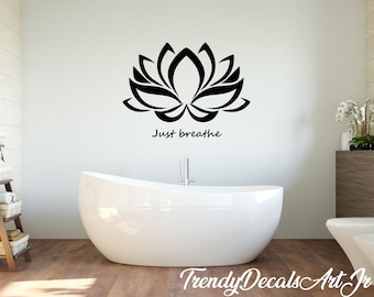 May include: Black and white wall decal featuring a stylized lotus flower with the text "Just breathe" underneath. The decal is displayed in a bathroom setting with a white bathtub and a wooden shelf.