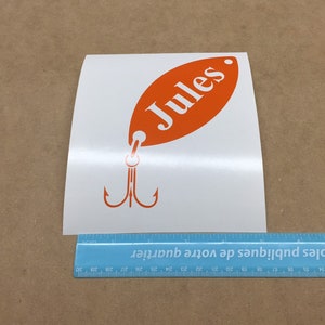 May include: Orange and white vinyl decal of a fishing lure with the name "Jules" on it.