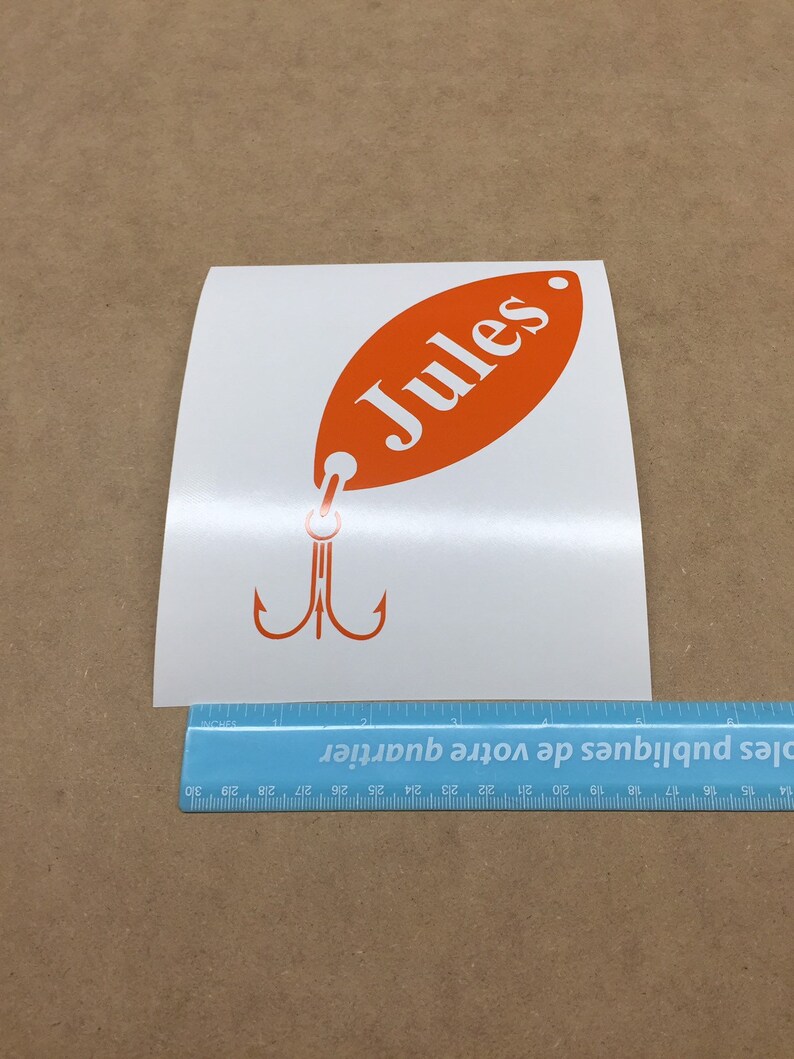 May include: Orange and white vinyl decal of a fishing lure with the name "Jules" on it.