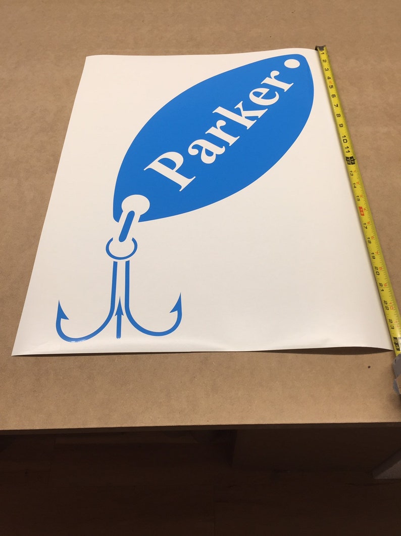 May include: A white vinyl decal of a blue fishing lure with a treble hook and the name "Parker" written on it.