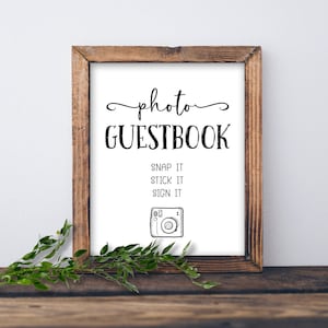 Può includere: Un cartello bianco con cornice in legno, che recita "photo guestbook" con le istruzioni "snap it, stick it, sign it" e un disegno di una macchina fotografica.