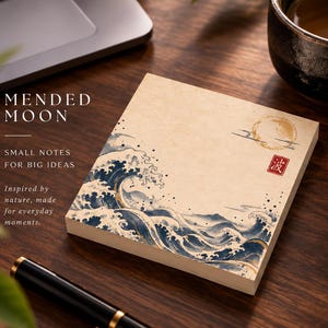 May include: A square notepad with a cream-colored background featuring a blue and white wave illustration, a golden moon, and a red square stamp with the Japanese character for wave. The text MENDED MOON, SMALL NOTES FOR BIG IDEAS is printed.