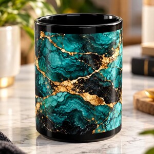 May include: A cylindrical ceramic mug featuring a vibrant teal and black marble pattern with prominent gold veining throughout the exterior. The interior of the mug is solid black, and the rim is finished with a smooth, glossy black edge.
