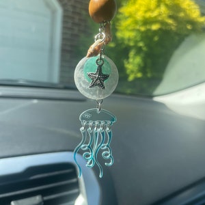 May include: A blue and clear plastic jellyfish car charm with a wooden bead, seashells, and a starfish charm hanging from it.