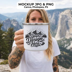 May include: White enamel camping mug with a silver rim, featuring a black and white mountain design and the text "Your Design Here." The mug is held up against a scenic mountain backdrop.