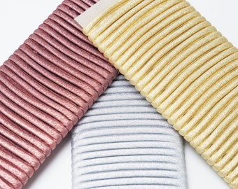 May include: Three different colors of elastic hair ties. The hair ties are made of a ribbed material and have a shimmery finish. The colors are rose gold, silver, and gold.