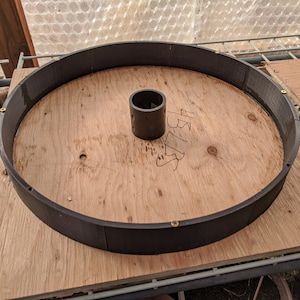 以下が含まれることがあります： 縁に黒いプラスチック製のリングが付いた円形の木製ベース。黒いプラスチック製のパイプがベースの中央にあります。ベースには数字の45が書かれています。