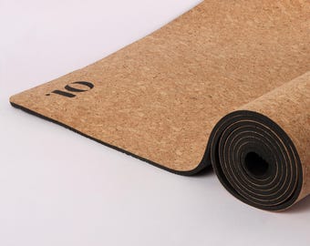 Op de afbeelding: Een opgerolde kurken yogamat met een zwarte rand en de tekst ".io" erop gedrukt.