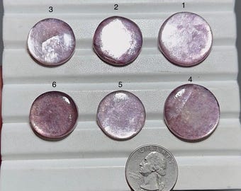 May include: Six round, polished, lavender-colored gemstones are displayed on a white tray. The gemstones have a reflective, iridescent quality. A U.S. quarter coin is included for size comparison. The gemstones are numbered 1 through 6.