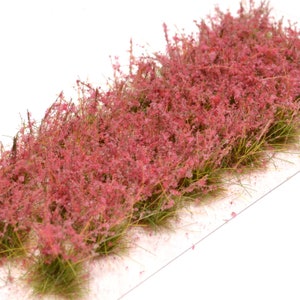 Könnte beinhalten: Eine Platte mit Modellbahn-Landschaftsmaterial mit einer Basis aus grünem Gras und einer Schicht aus rosa Blüten.