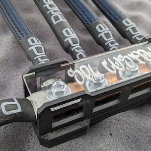 以下が含まれることがあります： 黒と透明の電気部品。4本の青と黒の編組ケーブルが付いています。ケーブルには白で「Pride」と書かれています。コンポーネントには白で「Spyderworks」と書かれています。電気用途向けに設計されています。