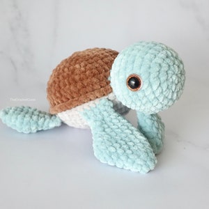 K&ouml;nnte beinhalten: Ein geh&auml;keltes Pl&uuml;sch-Schildkr&ouml;tenspielzeug mit brauner Schale, wei&szlig;em Bauch und hellblauen Gliedma&szlig;en. Die Schildkr&ouml;te hat gro&szlig;e, schwarze Augen.