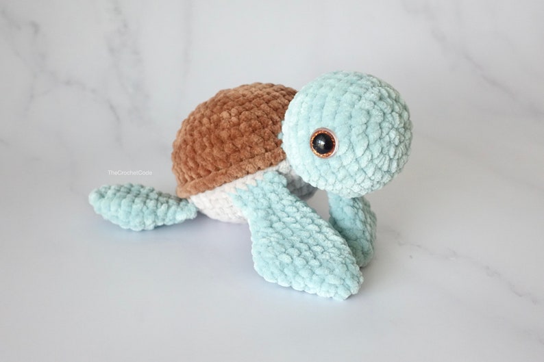 K&ouml;nnte beinhalten: Ein geh&auml;keltes Pl&uuml;sch-Schildkr&ouml;tenspielzeug mit brauner Schale, wei&szlig;em Bauch und hellblauen Gliedma&szlig;en. Die Schildkr&ouml;te hat gro&szlig;e, schwarze Augen.