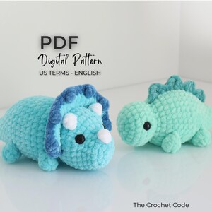 May include: Two crocheted dinosaur toys. One is a light blue triceratops with a dark blue frill and white horns. The other is a light green dinosaur with a spiky back. The text "PDF Digital Pattern US TERMS - ENGLISH" is at the top.