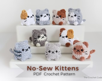 May include: A collection of eight crocheted kitten figurines in various colors, including white, gray, and brown. Each kitten has black embroidered facial features. The image includes text that reads "No-Sew Kittens PDF Crochet Pattern".