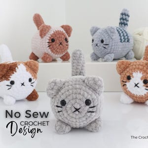 May include: A collection of handmade crochet cat toys in various colors, including white, gray, and brown. Each cat has a unique pattern and facial features. The text "No Sew Crochet Design" is visible.