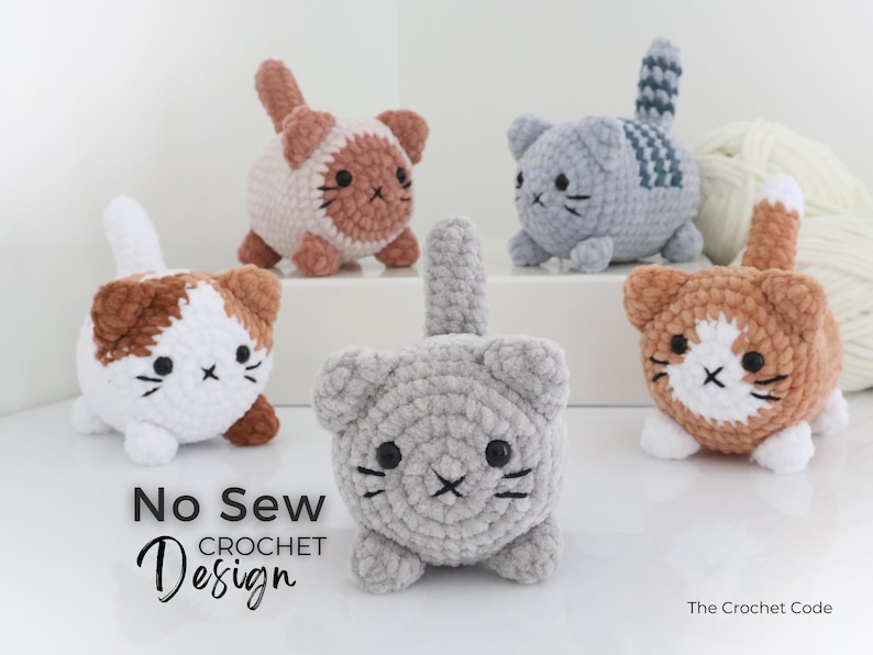 May include: A collection of handmade crochet cat toys in various colors, including white, gray, and brown. Each cat has a unique pattern and facial features. The text "No Sew Crochet Design" is visible.