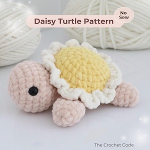 Puede incluir: Una tortuga de ganchillo hecha a mano con un diseño de caparazón de margarita. El cuerpo de la tortuga es de color rosa claro, con un caparazón de margarita amarillo y blanco. El texto "Daisy Turtle Pattern" se muestra en la imagen. The Crochet Code también se muestra.