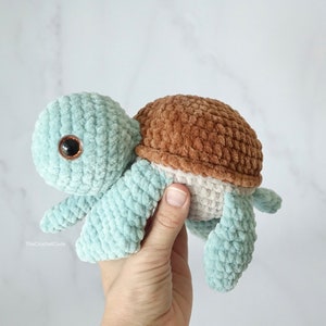 K&ouml;nnte beinhalten: Ein geh&auml;keltes Pl&uuml;sch-Schildkr&ouml;tenspielzeug mit einem hellblauen K&ouml;rper, einer braunen Schale und einem wei&szlig;en Bauch. Die Schildkr&ouml;te hat gro&szlig;e braune Augen.