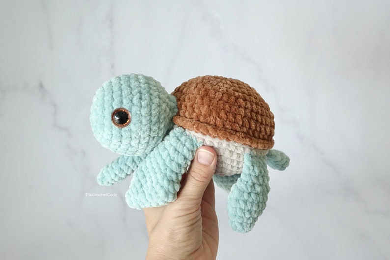 K&ouml;nnte beinhalten: Ein geh&auml;keltes Pl&uuml;sch-Schildkr&ouml;tenspielzeug mit einem hellblauen K&ouml;rper, einer braunen Schale und einem wei&szlig;en Bauch. Die Schildkr&ouml;te hat gro&szlig;e braune Augen.