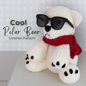 May include: A crocheted polar bear wearing black sunglasses and a red scarf. The bear has black paws and a black nose. Text on the image reads "Cool Polar Bear Crochet Pattern" and "The Crochet Code".