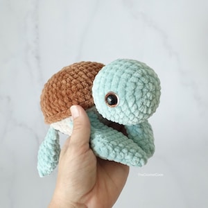 K&ouml;nnte beinhalten: Ein geh&auml;keltes Schildkr&ouml;tenspielzeug mit einer braunen Schale und einem hellblauen K&ouml;rper. Die Schildkr&ouml;te hat ein einzelnes schwarzes Auge.