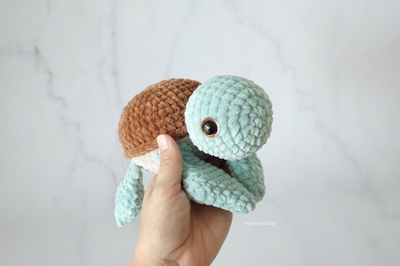 K&ouml;nnte beinhalten: Ein geh&auml;keltes Schildkr&ouml;tenspielzeug mit einer braunen Schale und einem hellblauen K&ouml;rper. Die Schildkr&ouml;te hat ein einzelnes schwarzes Auge.