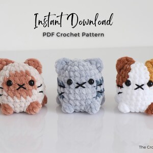 May include: Three crocheted cat toys in a row. The cats are in shades of brown, gray, and white. Each cat has black eyes and whiskers. The text "Instant Download PDF Crochet Pattern" is at the top of the image.