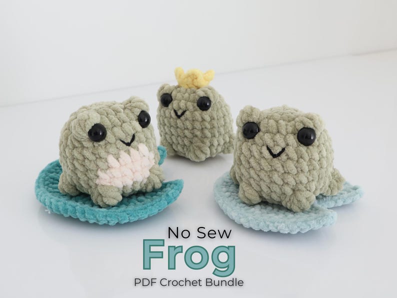 May include: Three handmade crochet frogs in shades of green and cream, each with black eyes and a smiling mouth. One frog wears a yellow crown. They sit on blue lily pads. The text "No Sew Frog PDF Crochet Bundle" is at the bottom.