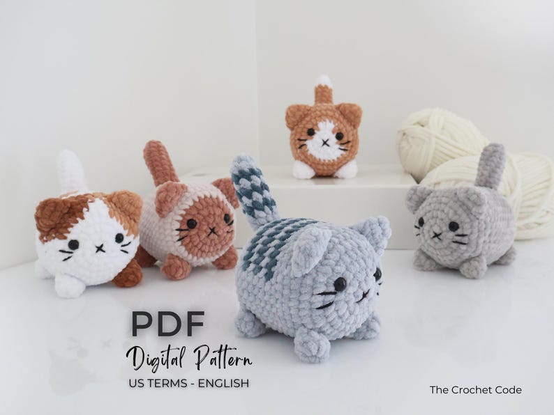 May include: A collection of handmade crochet cat figurines in various colors, including brown, white, and gray. Each cat has a unique design, with black whiskers and facial details. The image also includes yarn and text that says "PDF Digital Pattern".