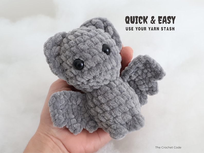May include: A gray crocheted bat plush toy with black eyes. The toy is being held in a person's hand. The text "QUICK & EASY USE YOUR YARN STASH" is above the toy. The text "The Crochet Code" is below the toy.