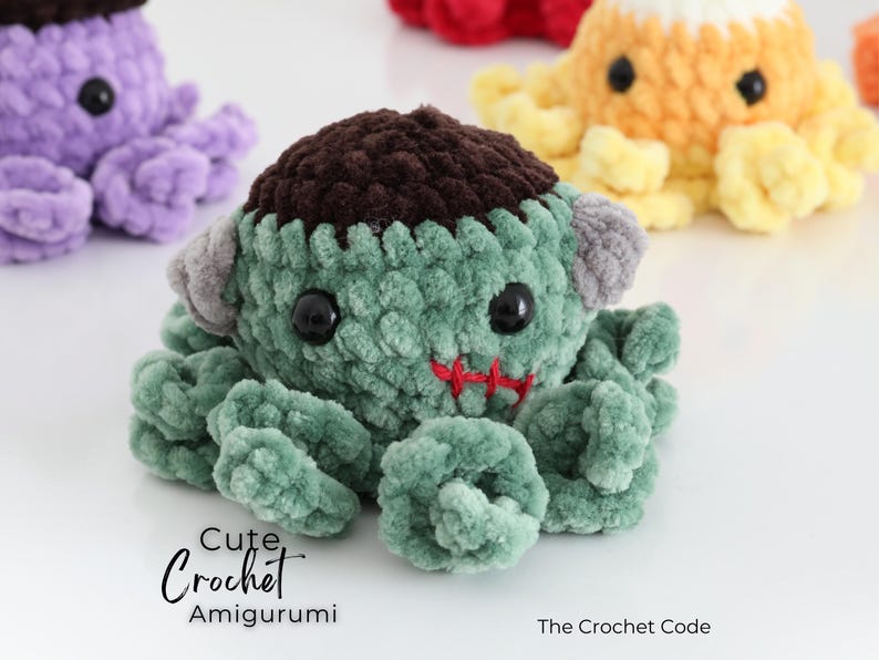 Puede incluir: Una criatura amigurumi de ganchillo verde con una parte superior marr&oacute;n oscura, pernos laterales grises y ojos de pl&aacute;stico negro. Presenta una boca cosida en rojo y tent&aacute;culos rizados. Texto: Cute Crochet Amigurumi y The Crochet Code.