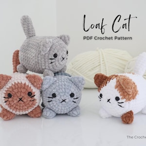 May include: Four crocheted cat toys in various colors: gray, white with brown patches, and pink with brown patches. Each cat has black embroidered facial features. The text "Loaf Cat PDF Crochet Pattern" is displayed in the image.