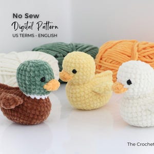 May include: Three crocheted ducklings in yellow, white, and brown with orange beaks and black eyes. The ducks are in front of balls of yarn in white, green, and orange. The text "No Sew Digital Pattern" is at the top.