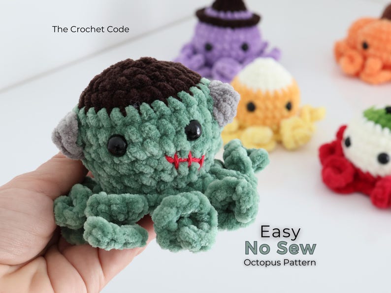 Puede incluir: Un pulpo de ganchillo verde con una parte superior marr&oacute;n oscuro, pernos grises en los lados y una boca cosida en rojo. El texto The Crochet Code y Easy No Sew Octopus Pattern es visible. Otros pulpos de ganchillo coloridos est&aacute;n al fondo.