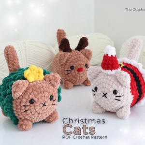 Peut inclure: Trois figurines de chats au crochet sur le thème de Noël. Un chat est décoré d'une couronne verte et d'une étoile jaune, un autre de bois de renne et le troisième d'un bonnet et d'un costume de Père Noël. Le texte "Christmas Cats PDF Crochet Pattern" est visible.