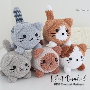 May include: A group of five crocheted cat toys in various colors, including gray, orange, and white. Each cat has black button eyes and embroidered details. The text "The Crochet Code" and "Instant Download PDF Crochet Pattern" are visible.